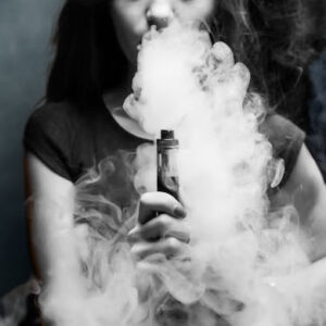 mulher soltando vapor após vaporizar vape