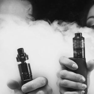 casal segurando cigarro eletrônico com atomizador a frente do corpo ao fundo de muita fumaça.