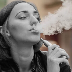 mulher de cabelo curto soltando fumaça após vaporizar cigarro eletrônico